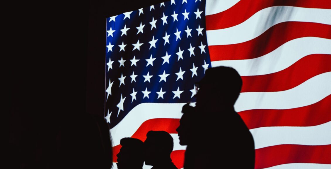 Zdjęcie amerykanskiej flagi i cienie postaci na jej tle