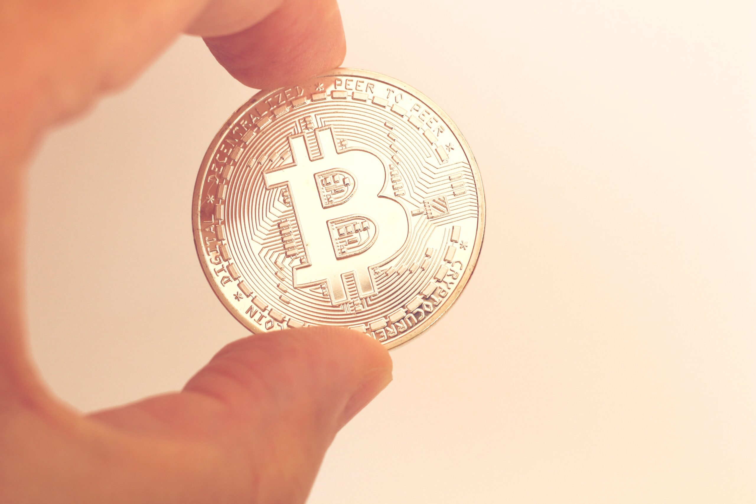 Złota moneta Bitcoina trzymana w ręce