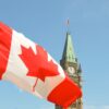 Zdjęcie kanadyjskiej flagi na tle ratuszu w Quebecu