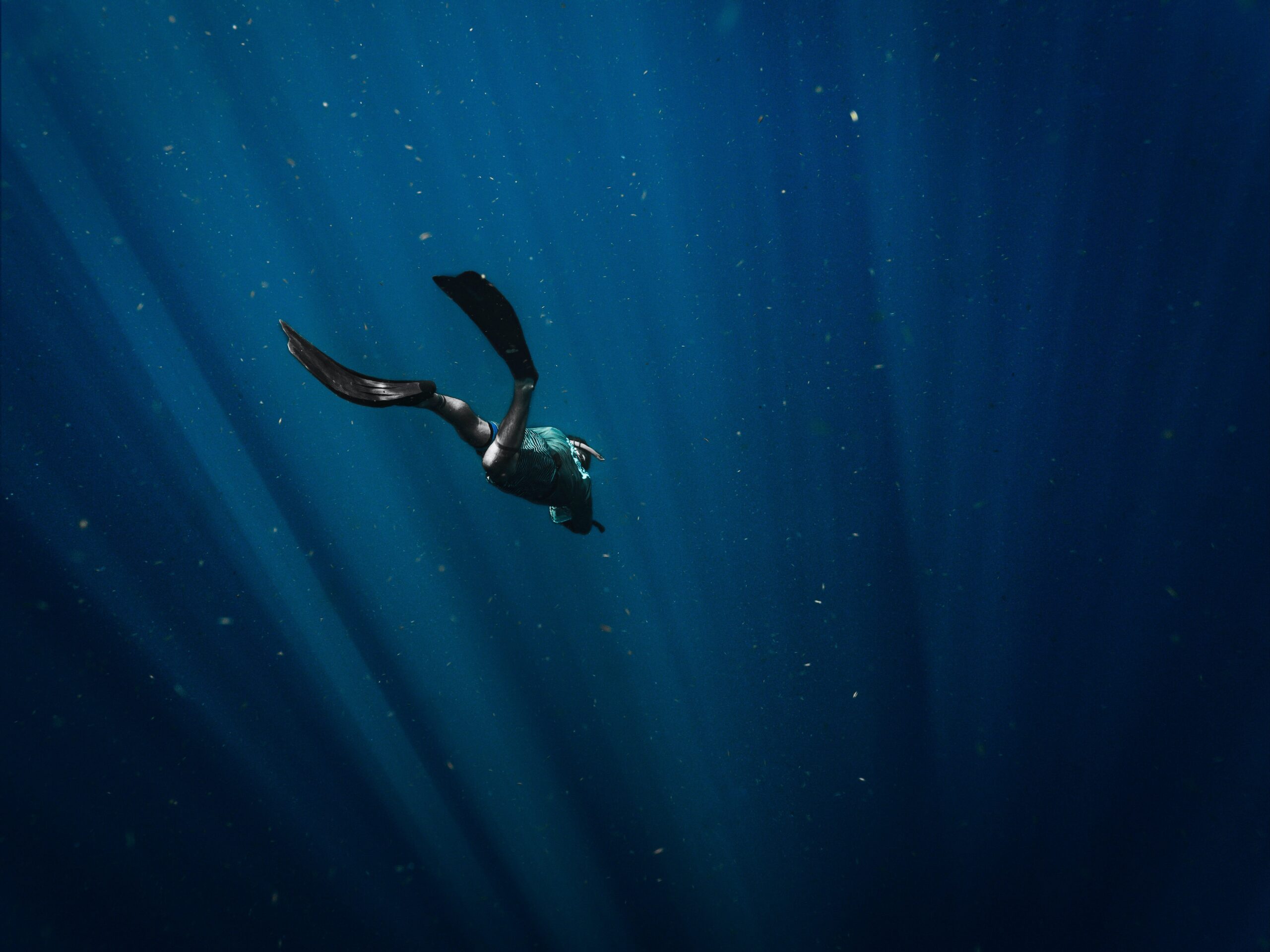 Zdjęcie nurka idącego pod wodę ciemnego oceanu