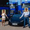 mężczyzna i kobieta z głowami nosacza sundajskiego na tle ciężarówek i lamborghini