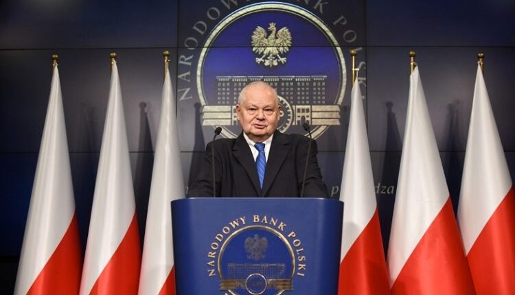 Adam Gklapinski na tle flag Polski i NBP