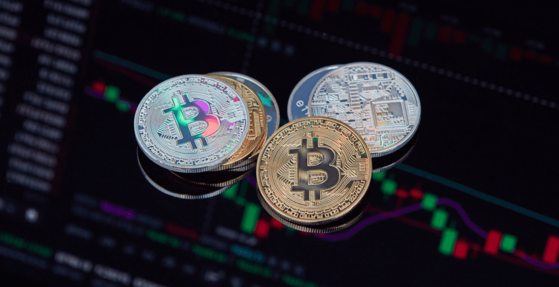 Monety reprezentujące kryptowaluty leżące na tablecie z wykresem giełdowym