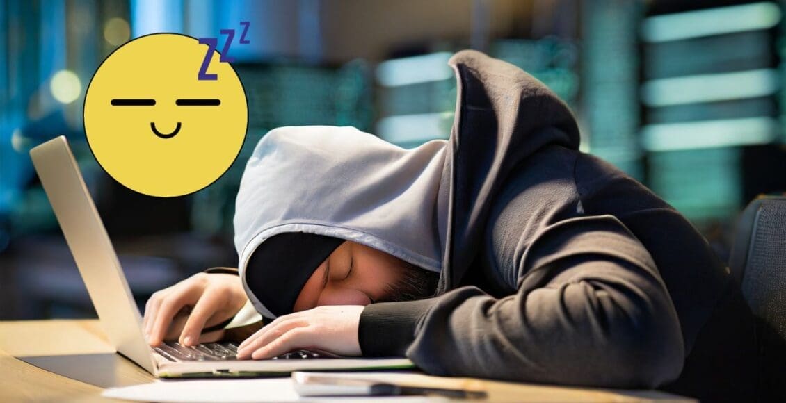 Zakapturzony haker śpiący na laptopie przy biurku