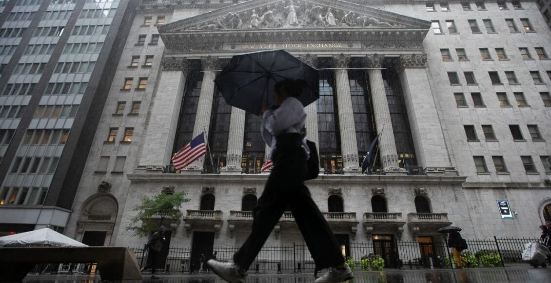 Człowiek pod parasolem spaceujący po Wall Street w Nowym Jorku