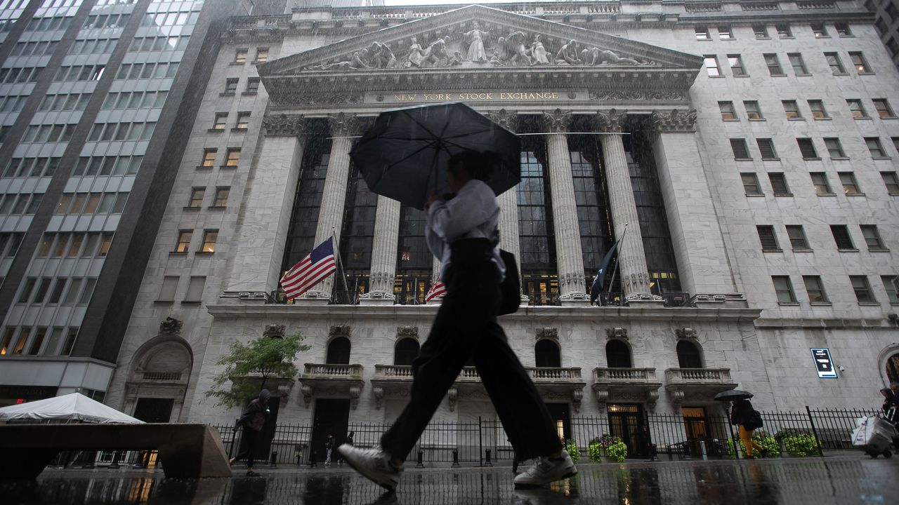 Człowiek pod parasolem spaceujący po Wall Street w Nowym Jorku