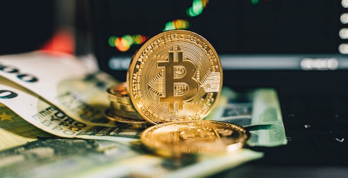 Monety z wizerunkiem Bitcoina przed wykresem cenowym