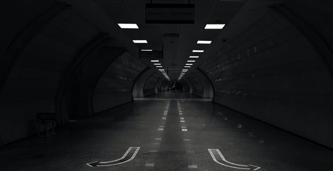 Ciemna droga w tunelu, z kilkoma światłami