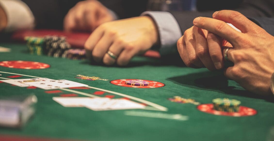 Ludzie siedzący przy stole, trzymający karty do gry w pokera