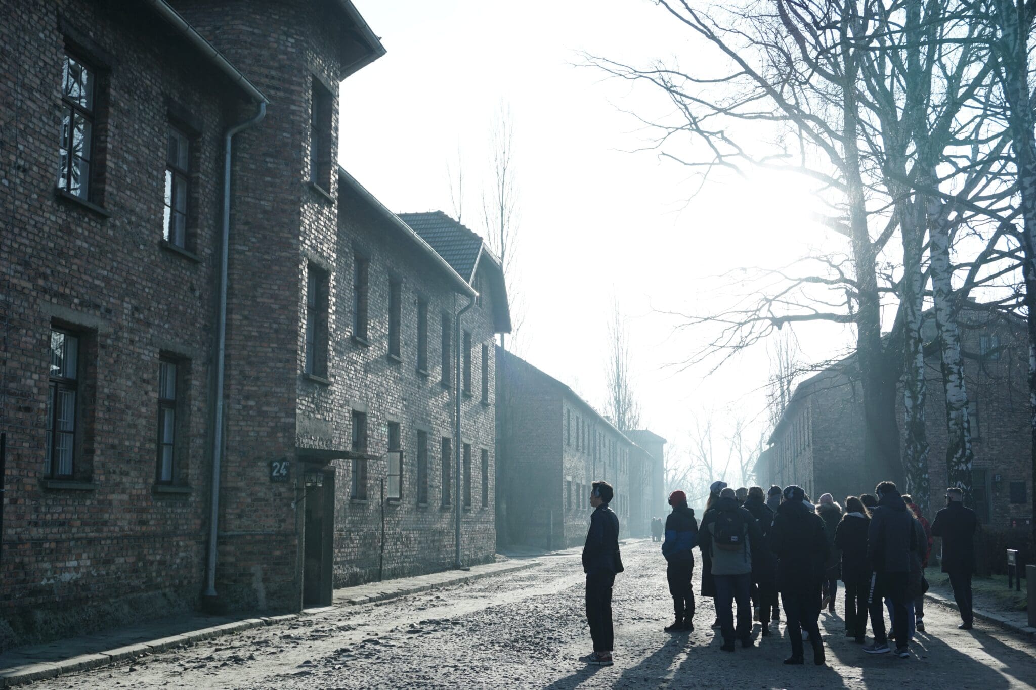 Ludzie stoją przed budynkami obozu koncentracyjnego