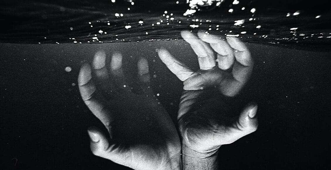 Ręka człowieka pod wodą, dotykająca tafli jeziora