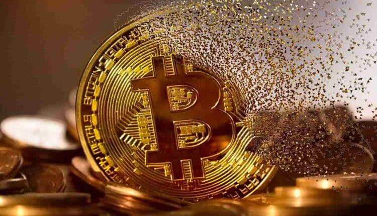 Bitcoin rozpadający się na drobne kawałki, leżący pośród złotych monet