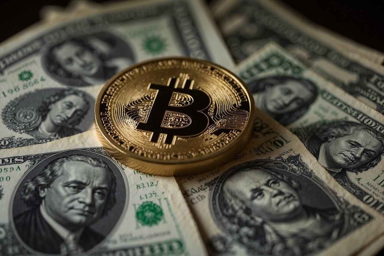Złota moneta Bitcoina leżąca na banknotach dolarowych.
