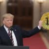Donald Trump trzymający w dłoni dużą złotą monetę Bitcoin