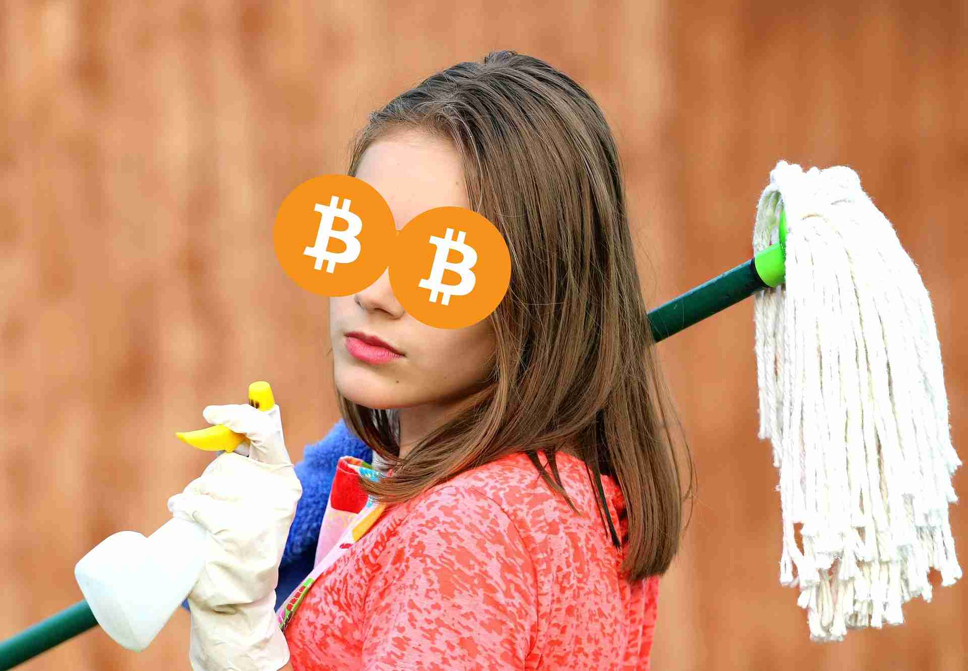 Kobieta w okularach Bitcoin, przygotowująca się do sprzątania. Trzyma mopa i spryskiwacz.
