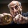 przewodniczący SEC Gary Gensler trzymający w dłoni monetę symbolizującą kryptowaluty