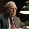 Zamyślony Warren Buffett siedzący przy biurku.