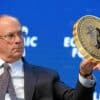 larry fink, ceo blackrock, trzymający monetę bitcoin