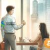 Mężczyzna w koszuli z logo Standard Chartered pokazujący gest kciuka w górę kobiecie, która siedzi na fotelu z logo Bitcoina.