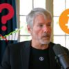 Michael Saylor w trakcie wywiadu, w tle Bitcoin i znak zapytania nad wykresami.
