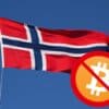 Zakaz Bitcoina, w tle powiewająca flaga Norwegii na błękitnym, bezchmurnym niebie.