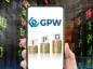 Debiut (IPO) na GPW. Smartfon z informacją i IPO na GPW na tle wykresów giełdowych.