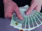 Dłonie trzymające wynagrodzenie w 100 zł banknotach.