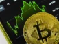 Bitcoin na tle smartfona, który wyświetla wykres wzrostu.