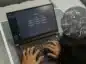 Laptop na którym pracuje człowiek, na ekranie widać ChatGPT, obok równania matematyczne