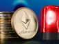 Stos tokenów Ethereum obok czerwonej lampki alarmowej.