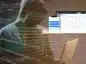 Zakapturzona postać przy laptopie na tle kodu programistycznego. W tle widok aplikacji desktopowej i smartfonowej Fakturownia