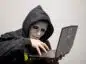 Haker w masce trzyma laptopa