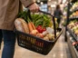 Klient niesie koszyk z podstawowymi produktami spożywczymi w sklepie, w tym warzywami, pieczywem, jajkami i olejem.