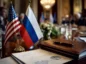 Flagi USA i Rosji na stole negocjacyjnym podczas spotkania gospodarczego G20, z dokumentami finansowymi w tle.