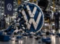 Rozsypujące się logo Volkswagena zbudowane z klocków na tle fabryki niemieckiego koncernu.