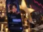 Smartfon z wirtualną postacią chatbota AI na ekranie, otoczony symbolami hollywoodzkiego przemysłu filmowego i dolarami. W tle czerwony spadający wykres symbolizujący problemy finansowe Character.AI.