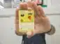Karta Pokemon z Pikachu z wschodnim alfabetem trzymana przez człowieka w taki sposób że nie widać jego twarzy karta jest skierowana do widza