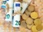 Plik banknotów waluty euro oraz leżące obok monety